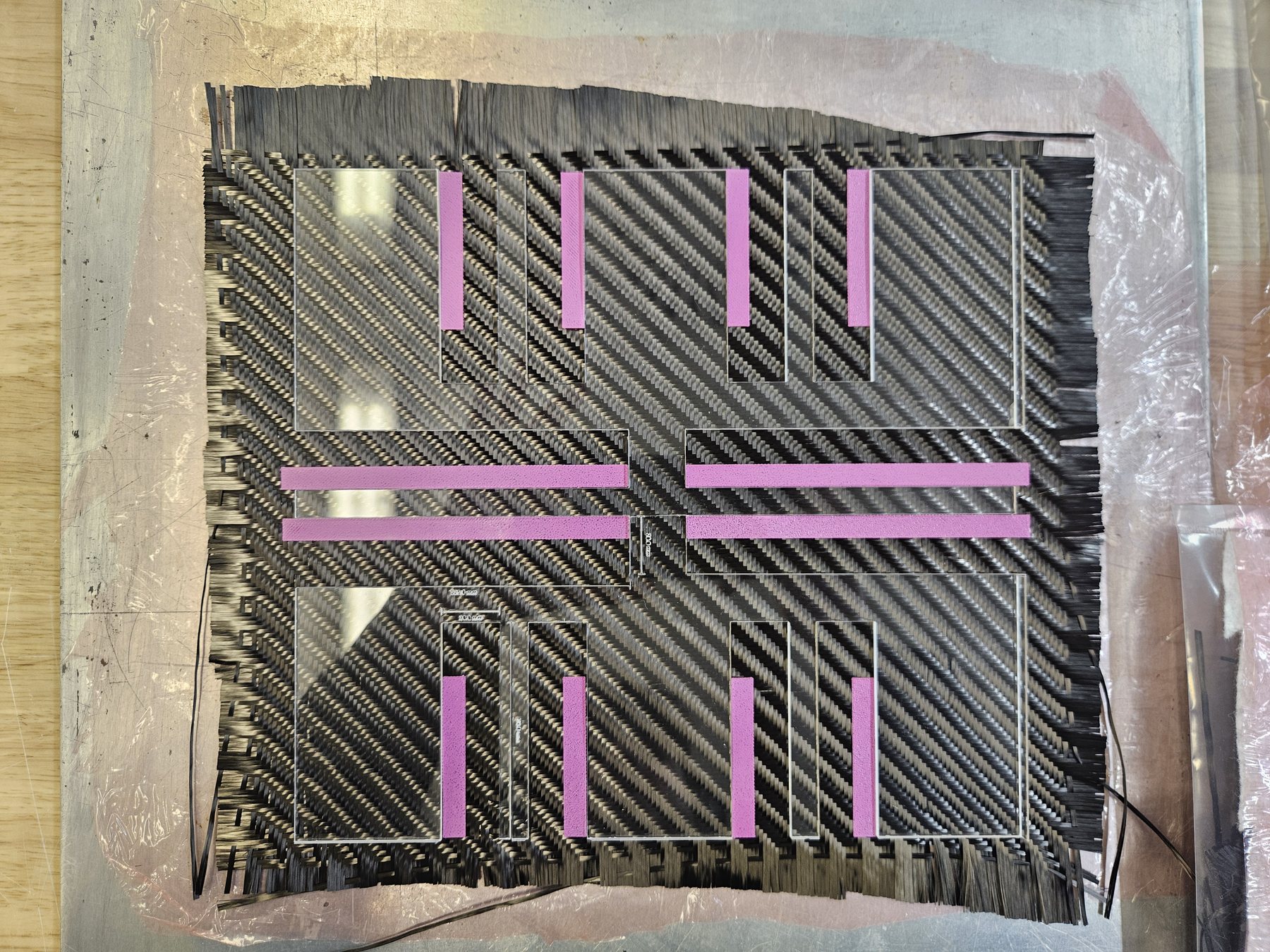 Acrylic positioning template and PLA patches on a carbon fabric specimen