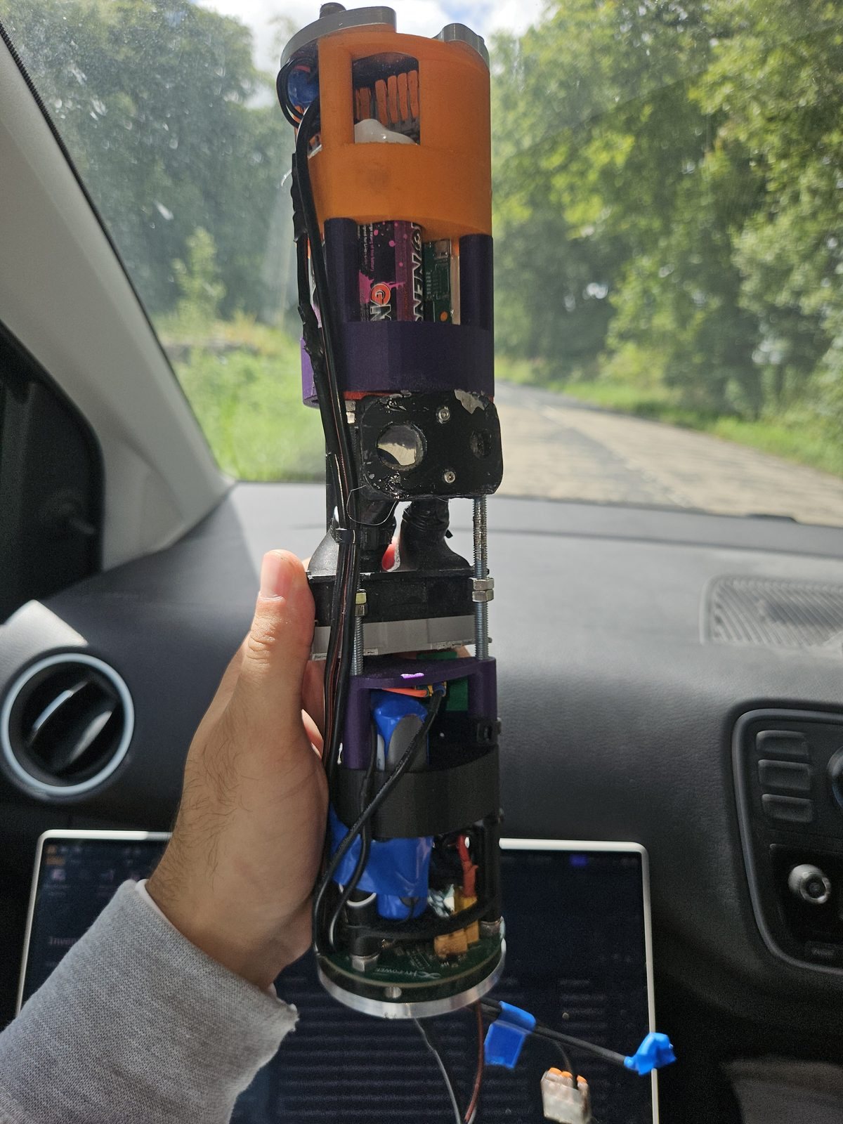 The assembled payload held up in a car, showing printed sections, wiring and the board