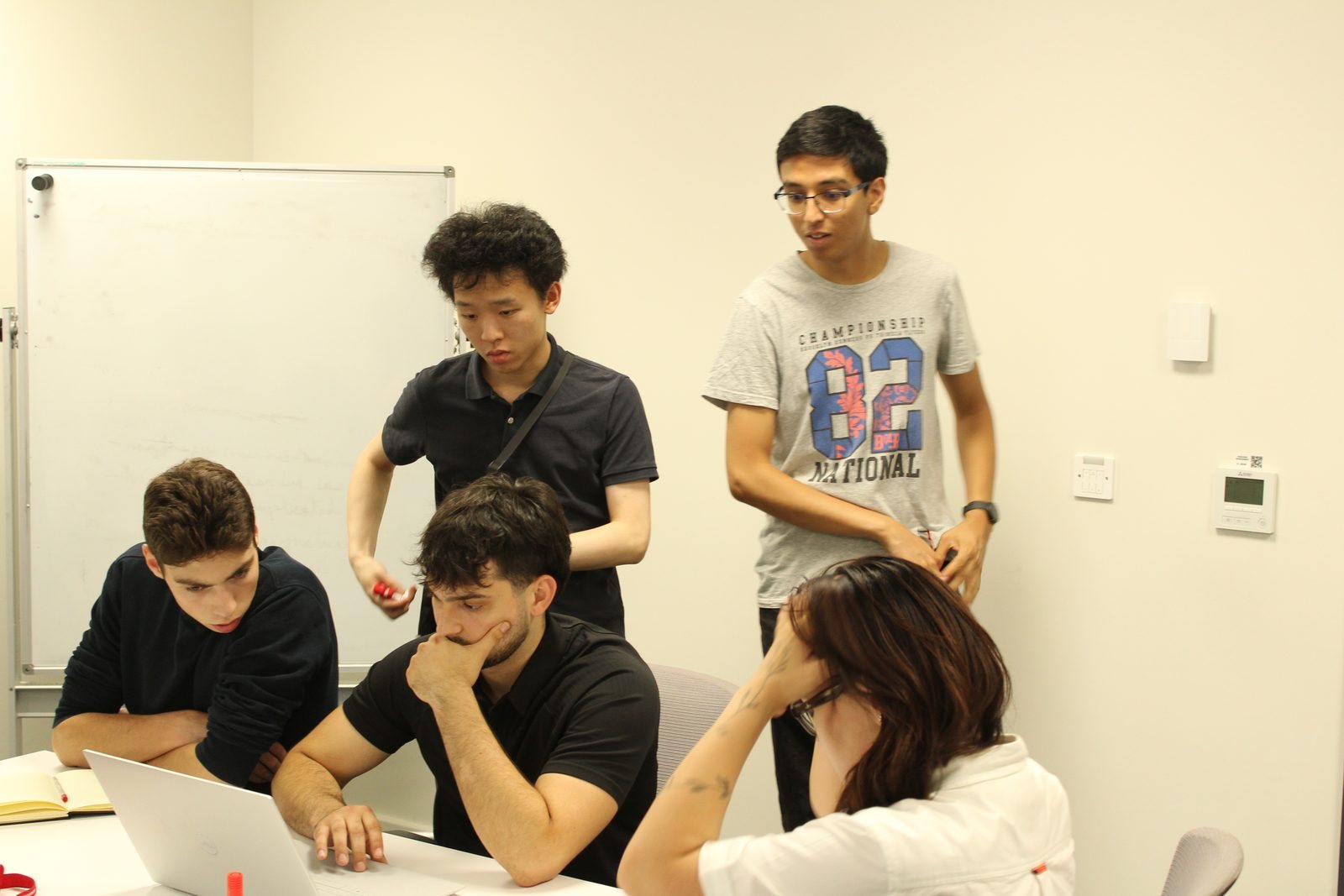 Team SLowMo around a laptop running the ground interface; Juan is seated with his hand on his chin
